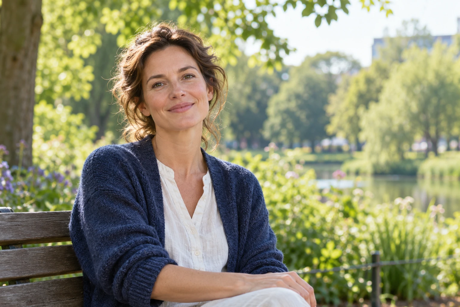 Vrouw zittend op parkbank, ontspannende glimlach, groen vijverlandschap op achtergrond